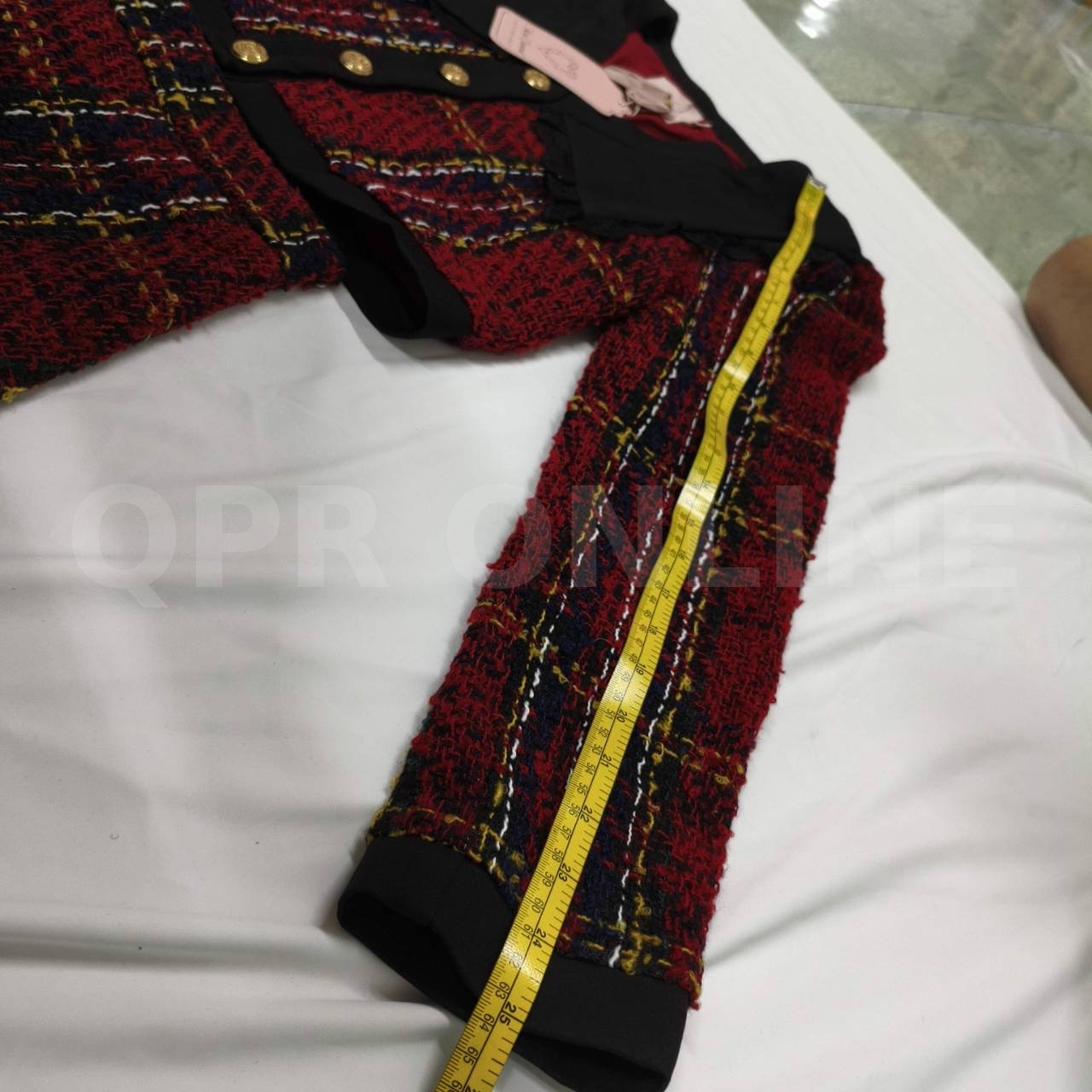มี (S) Maria Diamond เสื้อครอปแขนยาวผ้าทวีดทอลายตารางสีแดงสลับน้ำเงินและเหลือง โดดเด่นด้วยปกเสื้อสีดำขนาดใหญ่