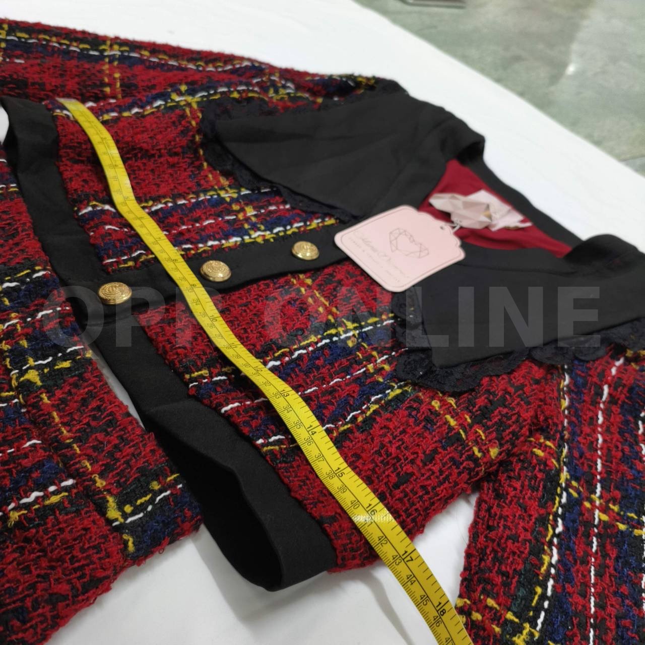 มี (S) Maria Diamond เสื้อครอปแขนยาวผ้าทวีดทอลายตารางสีแดงสลับน้ำเงินและเหลือง โดดเด่นด้วยปกเสื้อสีดำขนาดใหญ่